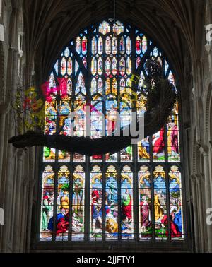 Sculpture en saule d'un ange censeur suspendue dans la nef de la cathédrale de Norwich, Norfolk. La fenêtre de vitraux ouest en arrière-plan. Banque D'Images