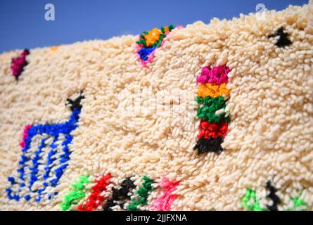 Les tisserands des vallées de l'ait Boulli et de l'ait Bougmez font les tapis de l'azilal. Les tapis azilal marocains sont un type de tapis berbère de la capitale provinciale du Maroc central dans les montagnes du Haut Atlas à environ 180 km de Marrakech. Ils sont faits de pure laine de mouton mélangée avec du coton et tissés horizontalement à l'aide d'une ligne quadrillée de nœuds. Les tapis du Maroc sont de haute qualité les rendant très durables, c'est pourquoi ils sont souvent trouvés dans les écoles, les bureaux, les maisons, et les zones de trafic élevé dans le monde entier. Ils résistent aux taches et sont généralement plus abordables que les tapis en peluche. Banque D'Images