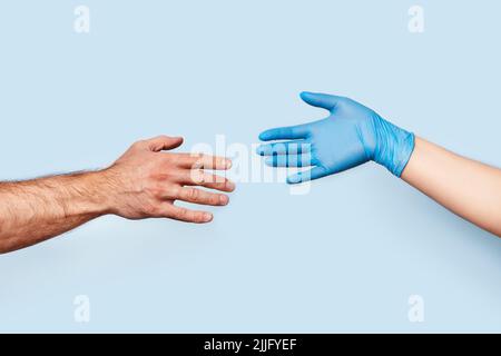 La main de l'homme et la main de la femme dans le gant en latex sont dessinées l'une à l'autre. La photo symbolise la distance sociale et la sécurité. Banque D'Images