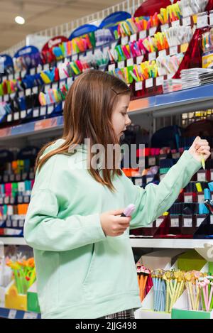 fille choisissant les fournitures scolaires dans le magasin de papeterie Banque D'Images