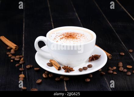 tasse blanche avec latte de café arrosée sur le dessus avec du chocolat ou du cacao sur un fond en bois noir ou foncé. Photo de haute qualité Banque D'Images