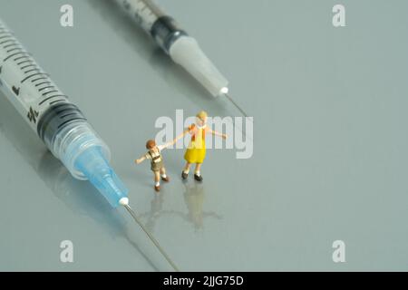 Photographie miniature de personnage de jouet de personnes. Concept de vaccination des enfants. Un enfant jouant à côté d'une seringue. Photo d'image Banque D'Images