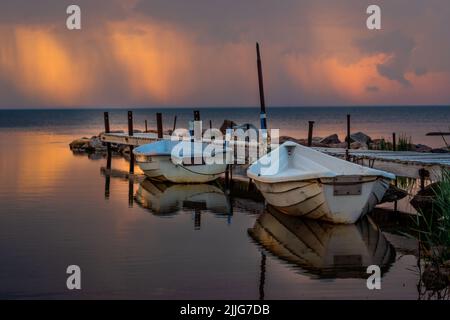 Deux bateaux de pêche locaux isolés sur un ancien quai en bois de la rustick dans le nord de l'Estonie. Photographié pendant un beau coucher de soleil coloré dans un oeil de la sto Banque D'Images