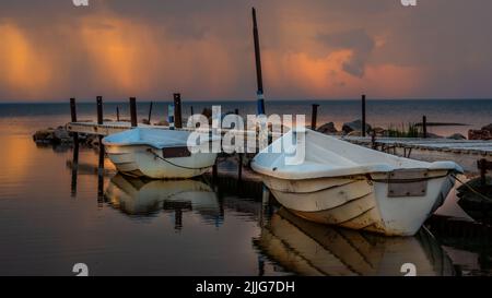 Deux bateaux de pêche locaux isolés sur un ancien quai en bois de la rustick dans le nord de l'Estonie. Photographié pendant un beau coucher de soleil coloré dans un oeil de la sto Banque D'Images