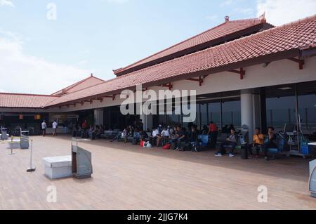 Les passagers attendent et se reposent avant de prendre un vol dans la zone fumeurs de l'aéroport international de Ngurah Rai à Bali, en Indonésie Banque D'Images