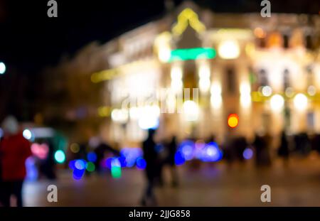 Arrière-plan flou. Silhouettes noires floues des gens, silhouette floue de bâtiment architectural illuminé par des lanternes, contre-jour la nuit. Place de la ville le soir. Il y a beaucoup de gens dans la rue Banque D'Images
