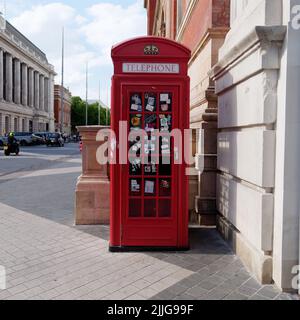 Londres, Grand Londres, Angleterre, 15 juin 2022 : boîte téléphonique rouge traditionnelle recouverte d'autocollants sur la route des expositions de South Kensington. Banque D'Images