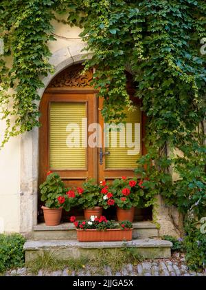 Ancienne maison et porte en bois avec fleurs rouges Banque D'Images