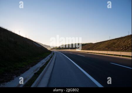 Une belle photo d'une route asphaltée étroite entre les collines à tour de rôle dans la campagne au coucher du soleil Banque D'Images