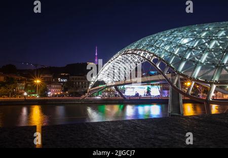 Pont de la paix Pont piétonnier en forme d'arc au-dessus de la rivière Kura dans la vieille ville de Tbilissi la capitale de la Géorgie. Prise de vue des lumières nocturnes. Banque D'Images