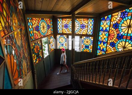 Une jeune femme touriste se promette dans des escaliers en bois avec de belles fenêtres colorées en mosaïque multicolore. Image concept voyager dans le monde. Banque D'Images