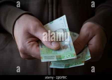 Un homme blanc qui donne des billets d'argent ukrainiens de près Banque D'Images