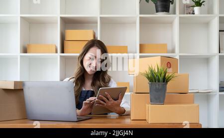 Portrait de démarrage de petites entreprises propriétaires de PME femmes entrepreneurs travaillant sur la boîte de réception et de vérifier les commandes en ligne pour se préparer à emballer les boîtes Banque D'Images