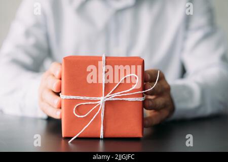 fête d'anniversaire d'entreprise papier rouge boîte cadeau mains Banque D'Images