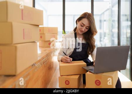 Jeune femme asiatique à l'entrepôt à la livraison à l'entrepreneur propriétaire PME. Entreprise numérique en ligne PME petite entreprise et boutique en ligne. Banque D'Images
