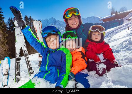 Les enfants et la mère, famille en vacances de ski, s'assoient ensemble dans la neige Banque D'Images