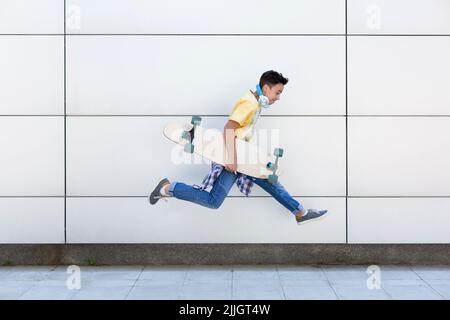 Adolescent de race blanche avec saut à la longue. Il est isolé sur un mur. Style de vie urbain. Espace pour le texte. Banque D'Images