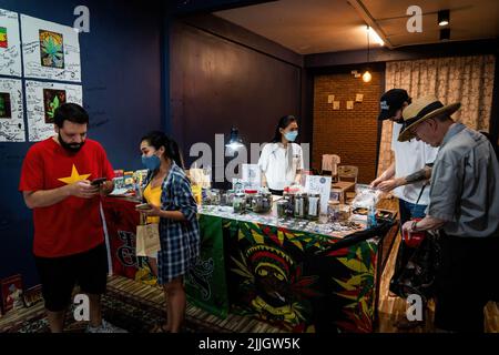 Les clients parcourent et effectuent des transactions numériques à côté d'une sélection de fleurs de cannabis à Fat Bud, un petit dispensaire de Bangkok qui se concentre sur l'achat et la vente de cannabis cultivé par les agriculteurs locaux en Thaïlande. Depuis que le Gouvernement thaïlandais a décriminalisé la vente et la possession de marijuana sur 9 juin 2022, des fleurs de cannabis sèches ont commencé à être vendues dans les dispensaires et dans la rue dans tout Bangkok. Un boom soudain de l'industrie de la marijuana, associé à sa légalisation rapide, se produit sans cadre solide pour la réglementation législative, ce qui entraîne une prévision économique incertaine pour l'industrie des mauvaises herbes Banque D'Images