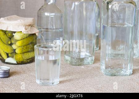 Verre de cristal et bouteille et concombre mariné sur fond de superposition Banque D'Images