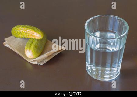 Verre de cristal et concombre mariné sur fond sombre Banque D'Images