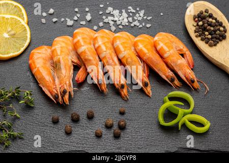 Crevettes sur panneau en pierre noire. Poireau et citron, piment d'allépice dans une cuillère. Pose à plat Banque D'Images