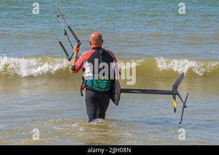 Kiteboarder / kitesurf entrant dans l'eau de mer avec un panneau de foilboard / hydrofoil Banque D'Images