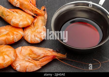 Crevettes bouillies et sauce soja dans un bol en métal. Vue de dessus. Arrière-plan noir. Banque D'Images