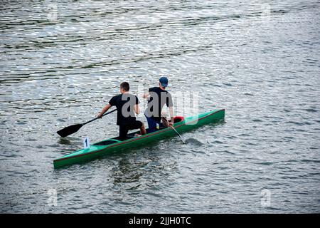 Deux jeunes athlètes en t-shirts noirs sont le canot de voile sur la rivière, contrôlant les oars. Entraînement sportif actif en plein air. Vue arrière. Copier l'espace. Chisinau, Mo Banque D'Images