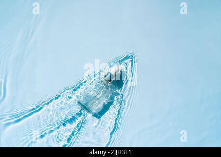 Sérum hydratant avec de l'acide hyaluronique en flacon sur fond d'eau avec vagues Banque D'Images