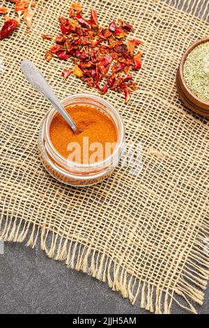 Paprika moulu dans un pot en verre sur toile de jute. Vue de dessus. Arrière-plan noir Banque D'Images