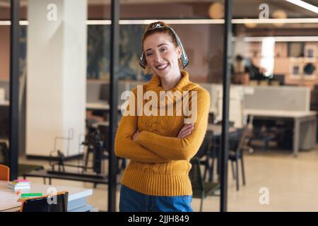 Portrait d'une femme d'affaires caucasienne d'âge moyen souriant debout avec les bras croisés au bureau Banque D'Images