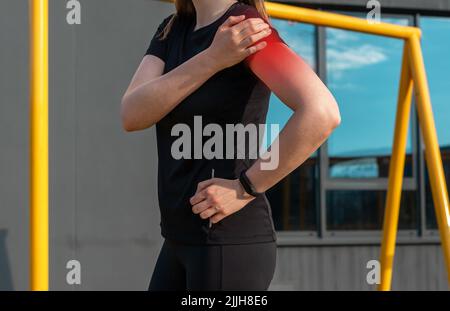 Athlète touchant l'épaule douloureuse avec le point rouge pendant l'entraînement en plein air. Dislocation, arthrite, fracture, conséquences de la déformation de la coiffe des rotateurs. Problèmes de santé dans le sport concept. Photo de haute qualité Banque D'Images