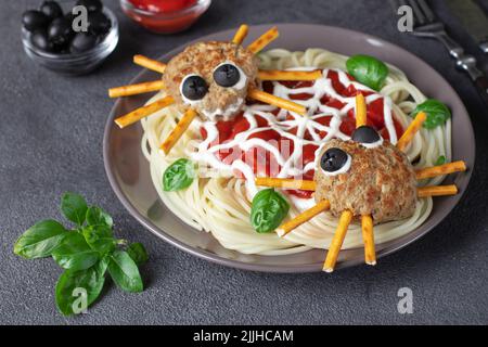 Les côtelettes ressemblent à des araignées aux olives et aux pailles, servies avec des pâtes spaghetti et de la sauce tomate. Idée petit déjeuner Halloween Banque D'Images