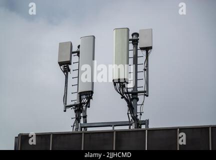 Les mâts de téléphone mobile ou de téléphone cellulaire au-dessus d'un immeuble de bureau Banque D'Images