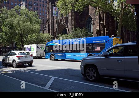 New York, NY, Etats-Unis - 25 juillet 2022: Un bus hybride moderne NYC avec les mots énergie propre sur le côté en gros caractères que le bus décharge passen Banque D'Images