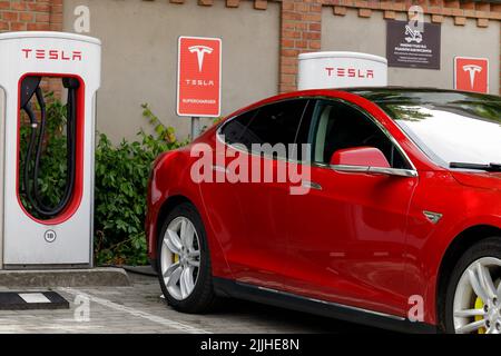 Poznan, Pologne. 26 juillet 2022 : voiture électrique lors de la charge dans une station de charge rapide de marque Tesla. Tesla rouge. Banque D'Images