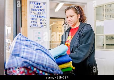 Une femme plie la blanchisserie à une laverie automatique, le 23 février 2013, à Columbus, Mississippi. Le travail paie le salaire minimum. Banque D'Images