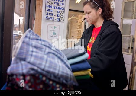 Une femme plie la blanchisserie à une laverie automatique, le 23 février 2013, à Columbus, Mississippi. Le travail paie le salaire minimum. Banque D'Images