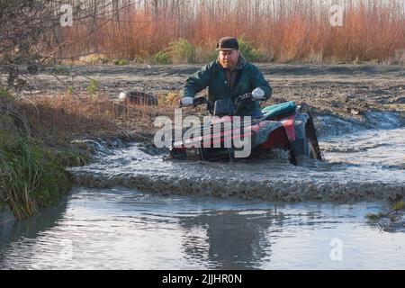 Un regard sur la vie en Nouvelle-Zélande: La pratique de passages de rivière et de boue sur le Quadbike: Souvent le seul moyen d'atteindre les meilleurs endroits de pêche. Banque D'Images