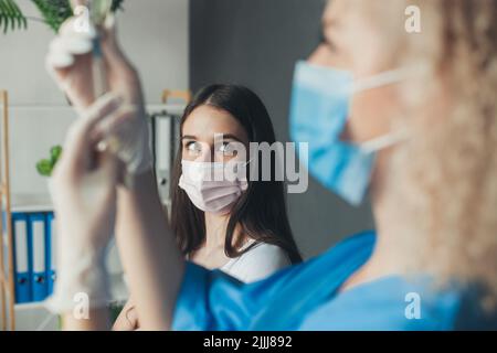 Infirmière préparant la seringue pour donner un cliché à une patiente effrayée. Prévention des pandémies. Prévention du coronavirus. Vaccination contre le coronavirus. Antiviral Banque D'Images