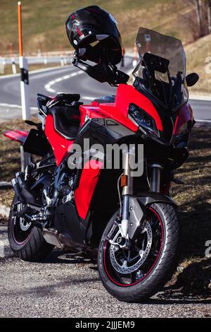 Une photo verticale d'un casque noir sur une moto BMW rouge avec des pièces en fibre de carbone Banque D'Images