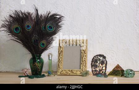 Vase de plumes de paon avec bijoux verts et cadre photo doré sur table avec fond en dentelle Banque D'Images