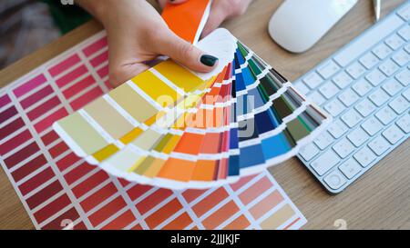 Femme de créateur tenant le ventilateur des échantillons colorés à la main Banque D'Images