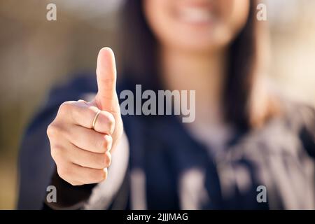 Qualifiée dans la carrière que je choisis d'avoir. Une femme méconnaissable montrant les pouces vers le haut le jour de la remise des diplômes. Banque D'Images