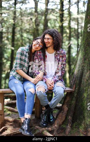 Jeune couple latin assis dans la forêt souriant au Costa Rica Banque D'Images