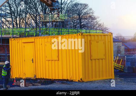 Constructeur installant le conteneur de la cabine du bureau du site. Installations de bien-être sur le chantier Banque D'Images