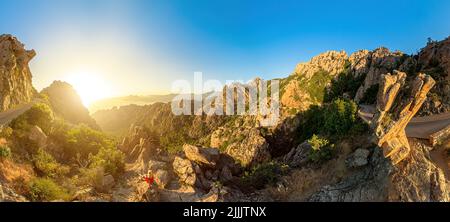 Vue aérienne 360 de la femme touristique sur la route D81 des calanques de Piana badlands au coucher du soleil. Vue de drone les Calanques dans les badlands corses Banque D'Images