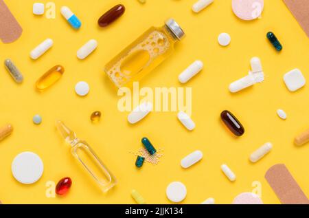Assortiment de comprimés et de pilules de médicaments à motif transparent avec flacon en verre d'ampoule et bracelet sur fond jaune vue du dessus plat Banque D'Images