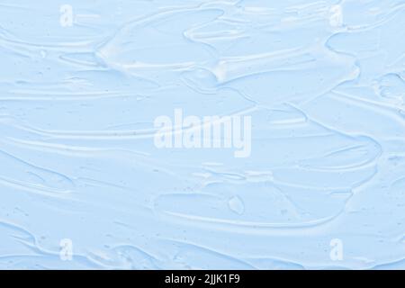 Sérum de crème gélifié transparent avec bulles sur fond bleu. Produits cosmétiques pour la peau texture du produit de beauté vue du dessus. Banque D'Images