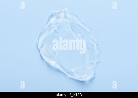 Gel cosmétique pour les soins de la peau frottis de sérum avec bulles isolées sur fond bleu vue de dessus Banque D'Images